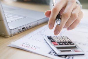 A hand with a pen using a calculator